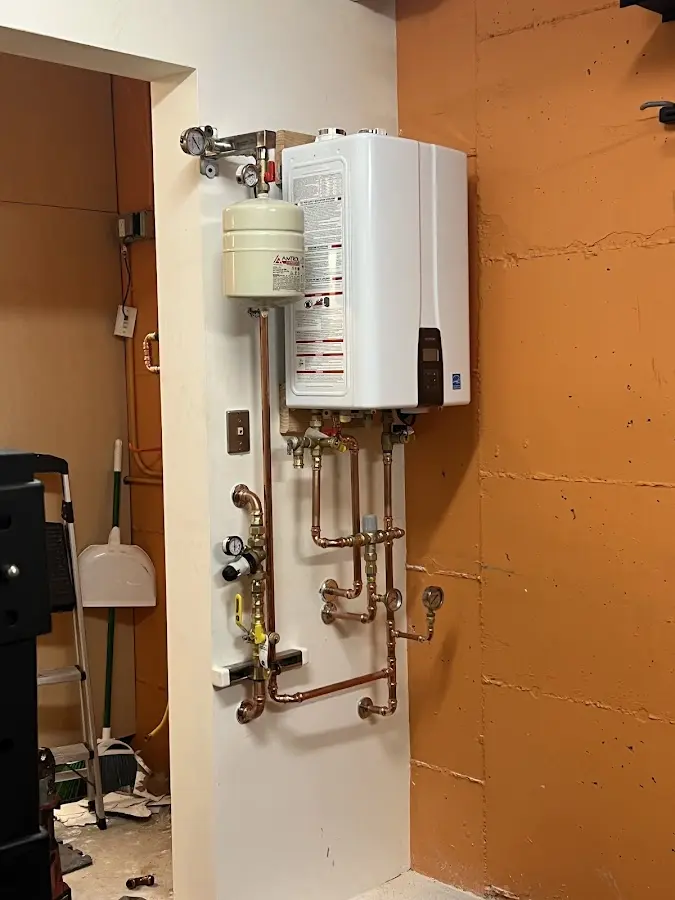 Plumbing technician inspecting water heater connections in Ladue